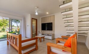 Ein modernes Wohnzimmer mit Flachbildfernseher, Holzmöbeln und einer Treppe.
