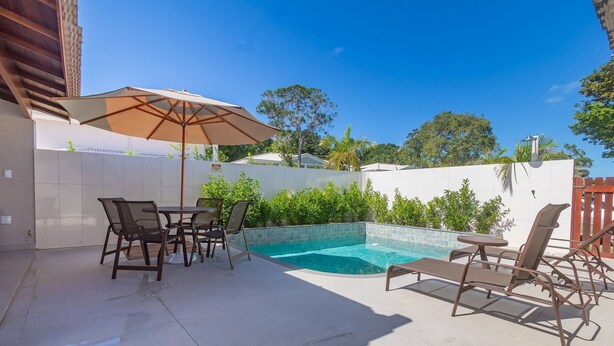 Ein Garten mit Swimmingpool, Terrassenmöbeln und einer überdachten Sitzgelegenheit.
