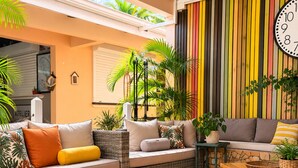 A cozy living room with a wicker sofa, a wooden coffee table, and a large wall clock. - Cozy Studio 150 meters from the beach (Les Trois-Îlets)