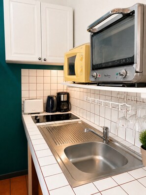 Eine Küche mit Spülbecken aus Edelstahl, einer Mikrowelle, einem Toaster und einer Kaffeemaschine.
