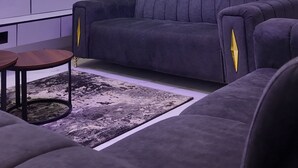 Un soggiorno moderno con un divano grigio, un tavolino da caffè e una televisione a schermo piatto montata a parete.