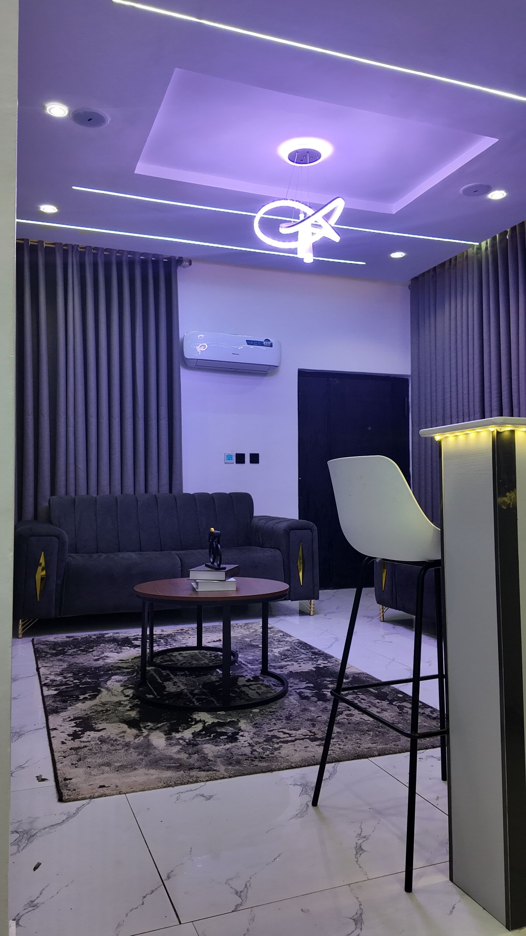 Una sala de estar moderna con un sofá, una mesa de centro, una silla y un mueble para televisión.