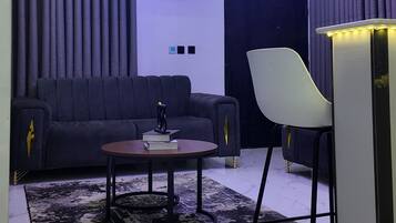 Una sala de estar moderna con un sofá, una mesa de centro, una silla y un mueble para televisión.