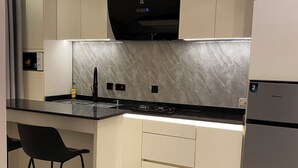 Una cucina moderna con zoccolo in marmo, forno integrato e frigorifero.