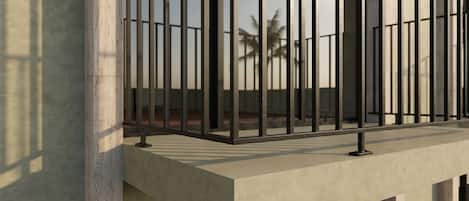 A modern balcony with a metal railing and a concrete ledge.