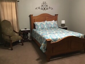 A bedroom with a wooden bed, a nightstand, a chair, and a wall decoration. - Lovely 1-bedroom guest house with AC in charming Bryan (Bryan)