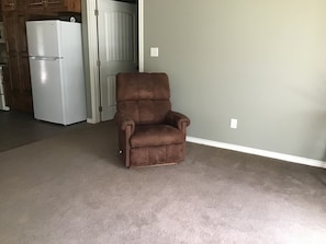 A brown recliner chair in a room with a grey carpet and a white door in the background. - Lovely 1-bedroom guest house with AC in charming Bryan (Bryan)