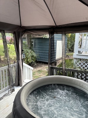 A hot tub under a covered patio with a view of a house and yard. - Perfect 2-bedroom cottage with AC in peaceful Livingston (Livingston)