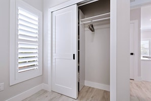 A white closet with a hanging rod and a door. - The Marina Suite - Near Downtown Sarasota Bayfront (Sarasota)