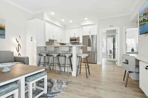 A modern kitchen with white cabinets, stainless steel appliances, and a central island with bar stools. - The New Downtown Sarasota Quadplex - Sleeps 24 (Sarasota)
