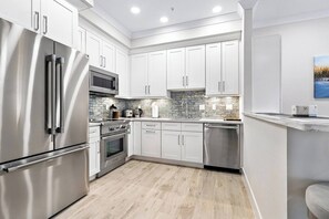 A modern kitchen with stainless steel appliances, white cabinetry, and a tiled backsplash. - Ringling Duo Suites - Downtown Sarasota, Sleeps 12 (Sarasota)