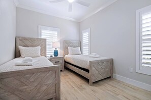 A bedroom with two wooden beds, a nightstand with a lamp, and a ceiling fan. - Ringling Duo Suites - Downtown Sarasota, Sleeps 12 (Sarasota)