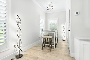 A modern interior with a dining area featuring a table and chairs, a decorative wall piece, and a ceiling light fixture. - Ringling Duo Suites - Downtown Sarasota, Sleeps 12 (Sarasota)