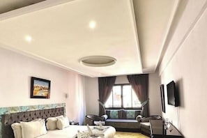 A hotel room with a bed, a window with curtains, a television, and a wall-mounted artwork. - Riad Dar Chafik (Marrakech)