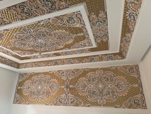 A ceiling with intricate, symmetrical patterns and a central light fixture. - Riad Dar Chafik (Marrakech)