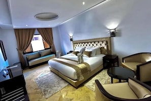 A hotel room with a large bed, a sofa, a small table, and a TV. - Riad Dar Chafik (Marrakech)