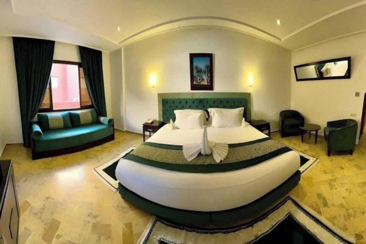 A hotel room with a large bed, a sofa, a desk, and a chair.