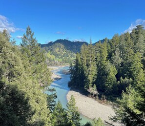 A river flowing through a forested valley with a clear sky.