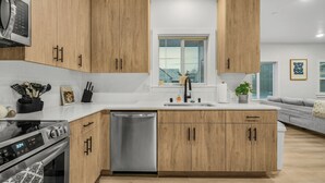 A modern kitchen with wooden cabinets, a stainless steel dishwasher, and a built-in oven.