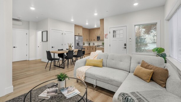 A modern living room with a grey sofa, a coffee table, and a dining area with a table and chairs.