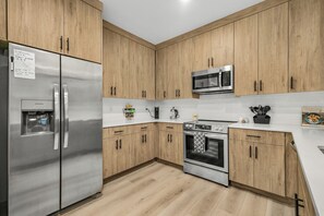 A modern kitchen with wooden cabinets, stainless steel appliances, a water dispenser, and a coffee maker.