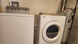 Un área de lavandería compacta con lavadora y secadora de carga frontal, medidor de servicios públicos y calentador de agua.
