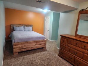 Une chambre à coucher avec un lit en bois, une commode et une porte.