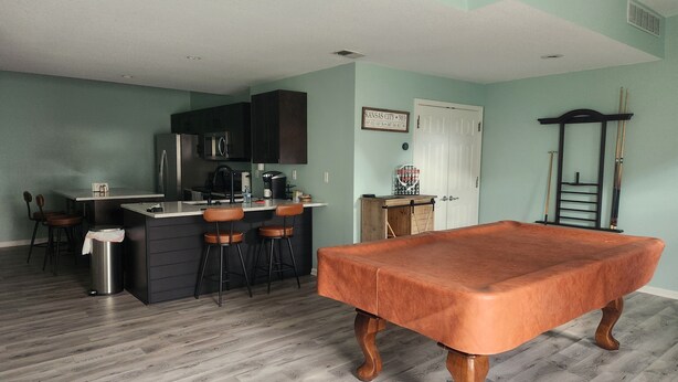 Una cocina con barra, mesa de billar y una puerta con letrero.