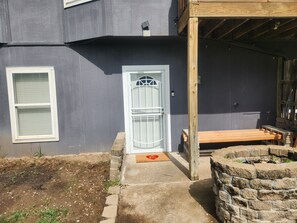 Uma casa com porta da frente, um banco de madeira e um muro de pedra.