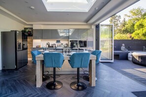 A modern kitchen with a central island, bar stools, and a dining table. - 4 Bedroom Luxury Home Features Hottub & Pool Table (Northwood)