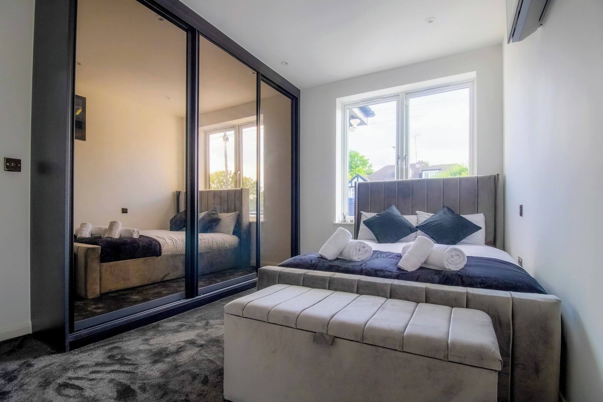 A bedroom with a large bed, a sliding glass door leading to a balcony, and a window providing natural light.