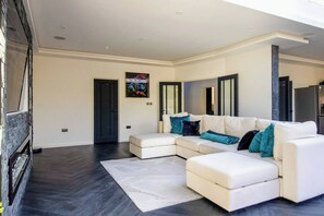A modern living room with a sectional sofa, a fireplace, and a large mirror. - 4 Bedroom Luxury Home Features Hottub & Pool Table (Northwood)
