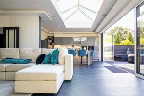 A modern living room with a sofa, a dining area, and a kitchen. - 4 Bedroom Luxury Home Features Hottub & Pool Table (Northwood)