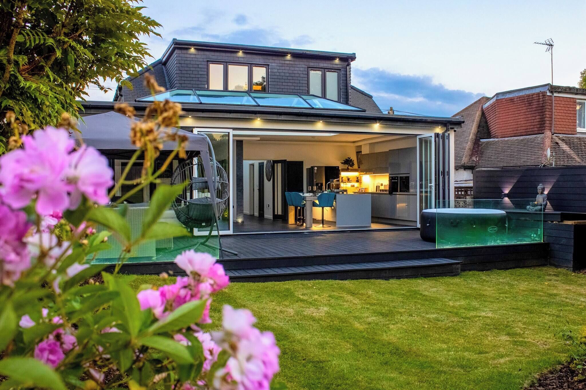 A modern house with a covered patio, a visible kitchen area, and a swimming pool.
