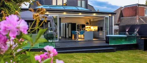 A modern house with a covered patio, a visible kitchen area, and a swimming pool.