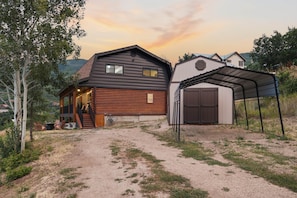 A two-story log cabin with a covered porch and a garage. - Midway Mountain Cabin (Wasatch County)