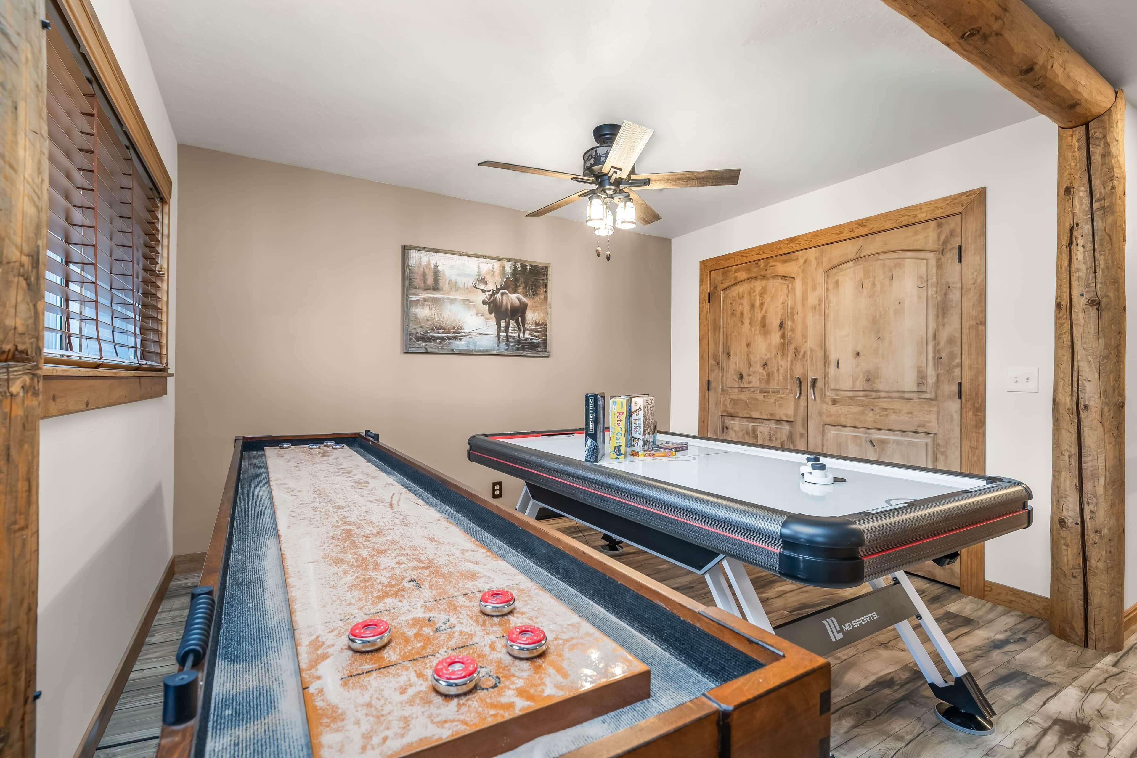 Une pièce avec une table de jeu de palet, un ventilateur de plafond et une porte en bois.