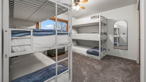 Habitación con literas, ventilador de techo, ventana con vistas y espejo en la pared.
