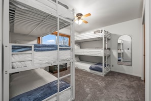 A bunk bed room with a ceiling fan, a window with a view, and a mirror on the wall. - Midway Mountain Cabin (Wasatch County)