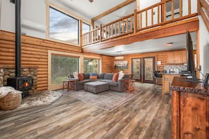 A log cabin interior with a fireplace, a large sofa, a dining area, and a kitchen. - Midway Mountain Cabin (Wasatch County)