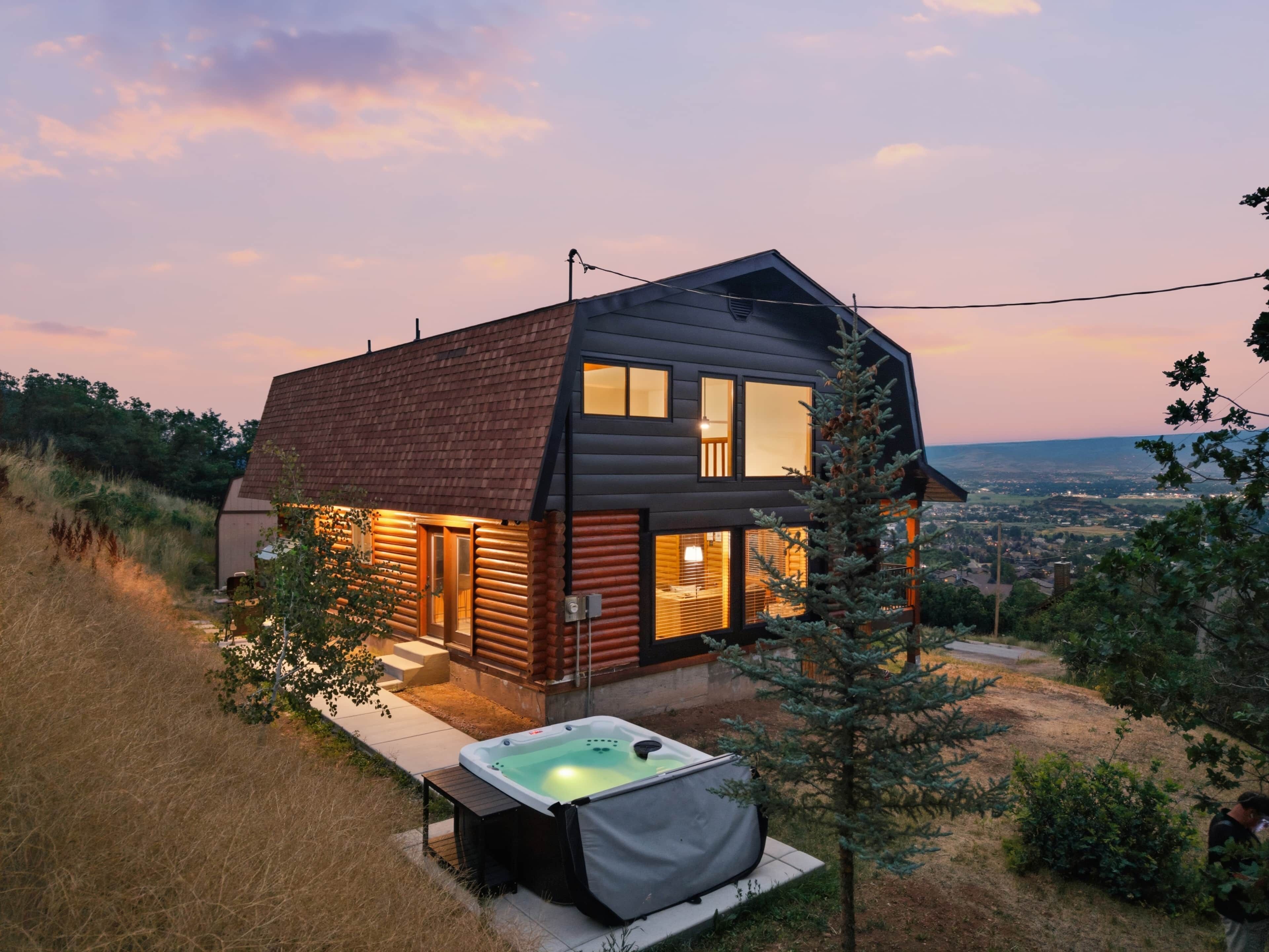 Una cabaña rústica moderna con jacuzzi y vistas panorámicas.