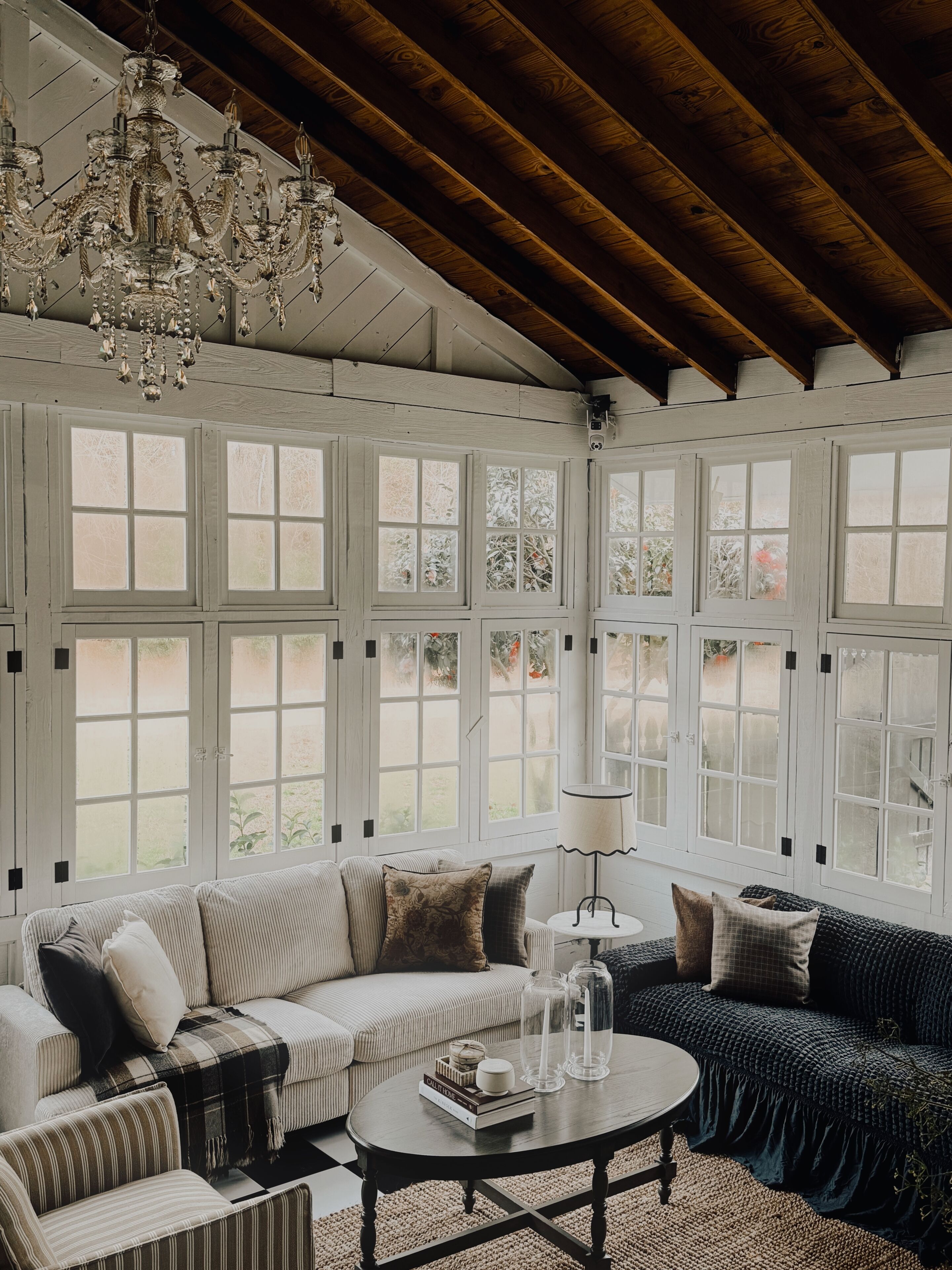 A cozy living room with a large window, a chandelier, and a sofa set.