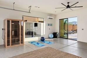 A spacious room with a sliding glass door leading to a patio, a ceiling fan, and exercise balls on the floor.