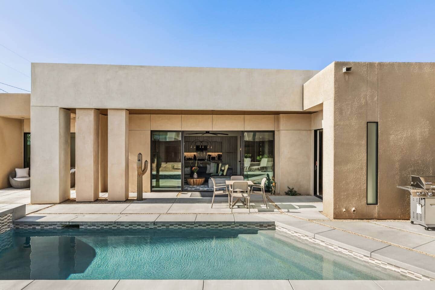 A modern house with a swimming pool, outdoor seating, and a garage.