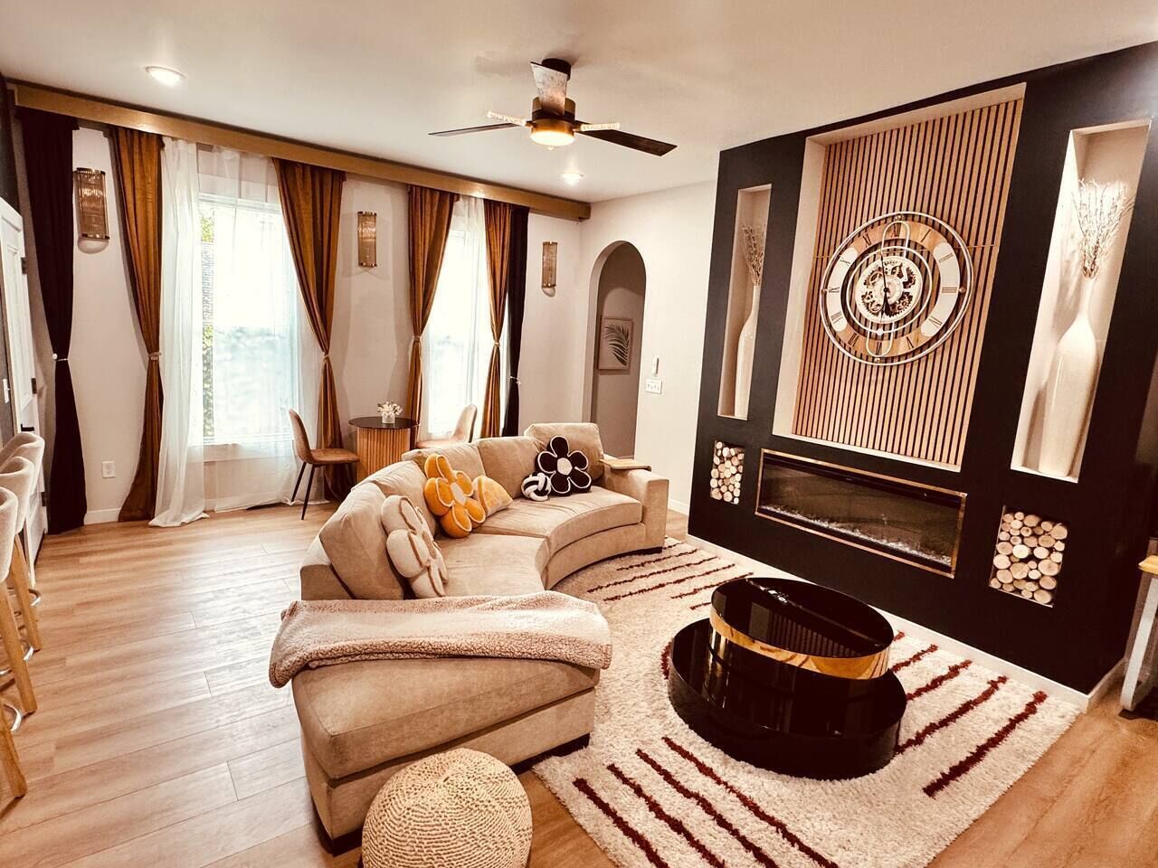 Un salon moderne avec un canapé d’angle, une cheminée et un ventilateur de plafond.