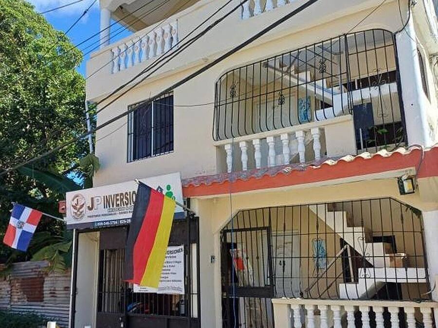 A two-story building with a sign for 'JP Inversion' and a flag.