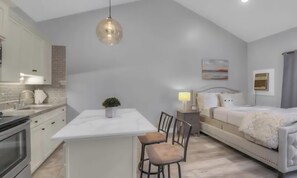 Een moderne keuken met witte kasten, een centraal eiland en een hangende pendelarmatuur.