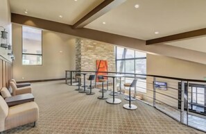 A spacious indoor area with a high ceiling, a stone wall, and a seating area with tables and chairs. - Stylish ParkCity Boutique studio with effortless access to slopes +Free Parking (Park City)
