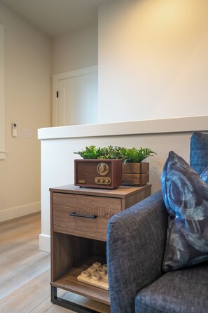 A modern living room with a wooden side table, a radio, and a plant. - Luxury Home in Heart of Vancouver / Quiet & Cozy (Vancouver)