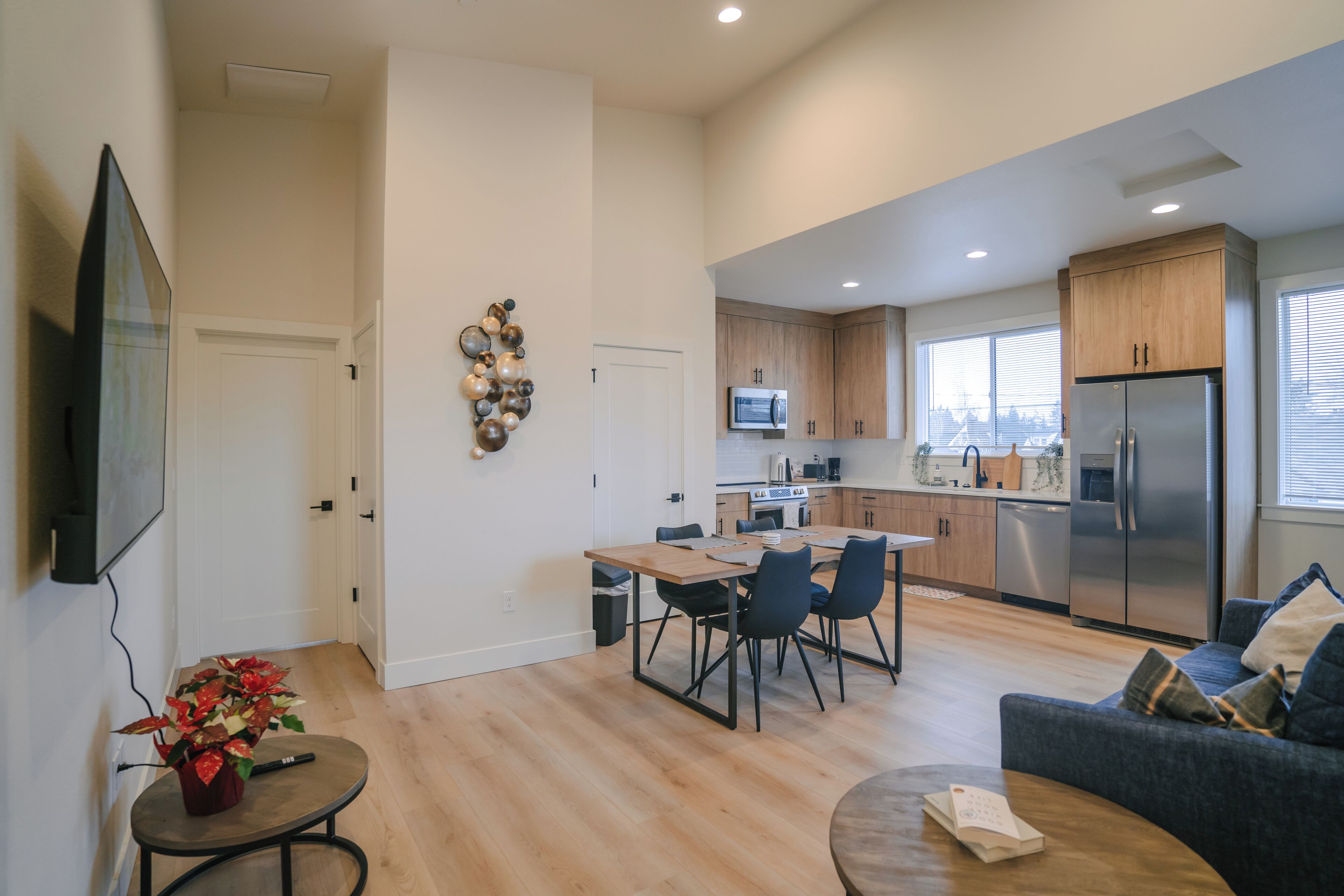 Una cocina moderna con electrodomésticos de acero inoxidable, un comedor con mesa y sillas de madera, y una sala de estar con sofá y mesa de centro.